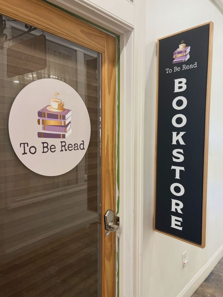 The To Be Read storefront — a round logo decal on the glass door beside a tall black BOOKSTORE sign